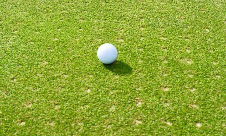 Golf ball lies on aerated green.