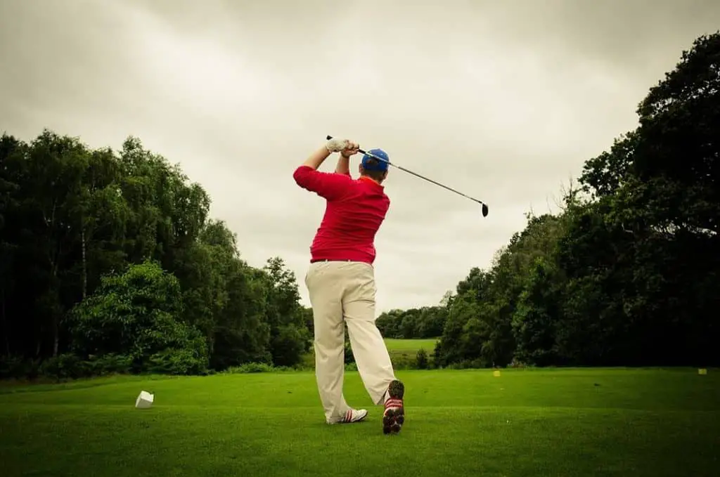 Golfer plays be himself on a green golf course.