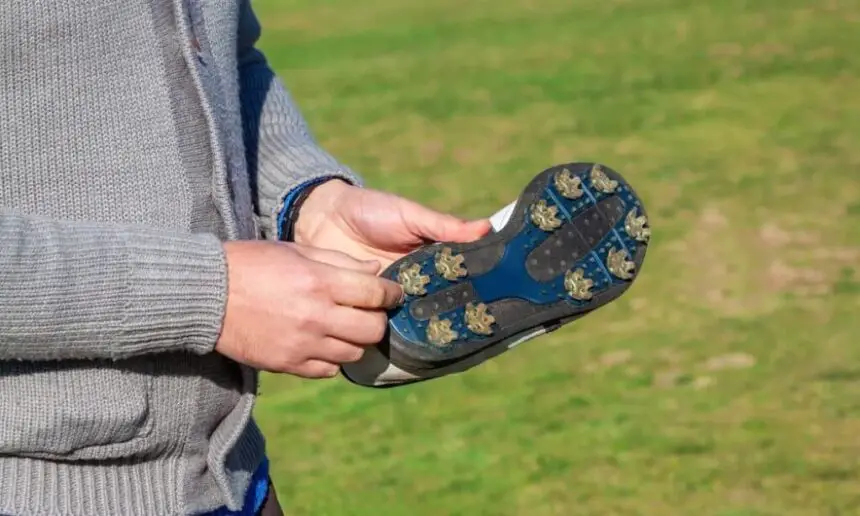 Golfer showing a golf shoe with spikes.
