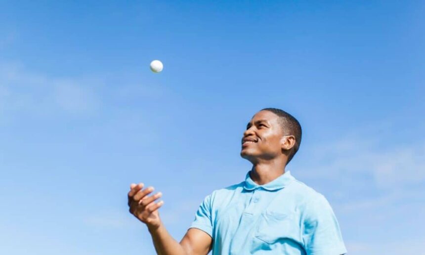 A man throws a golf ball in the air.