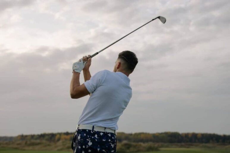 Golfer hitting a ball with an affinity golf club.