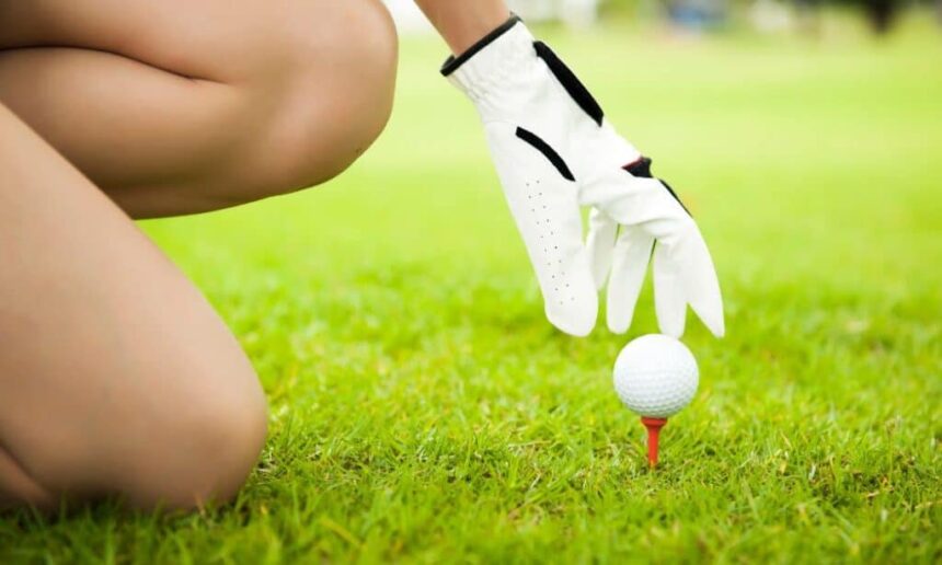 Female golfer placing ball on ladies tee.