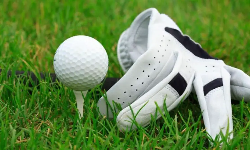 Golf glove and golf ball lie on the green.